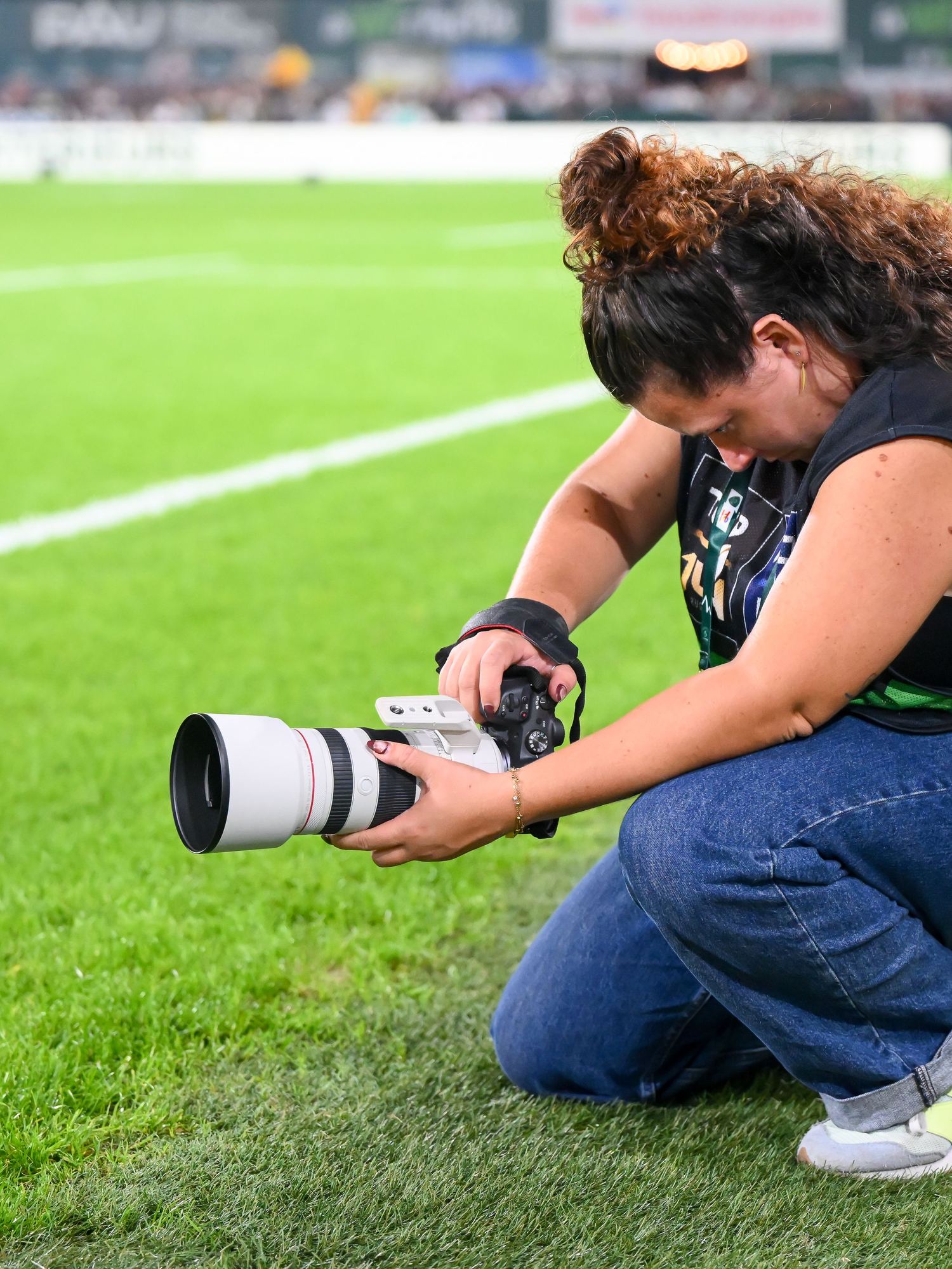 Maëlys accroupie en bord de terrain, photographiant un match de Top 14